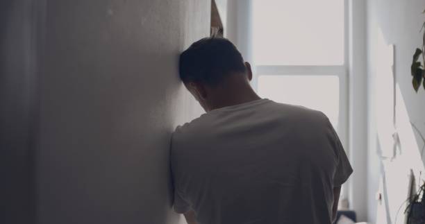 istock Depressed man in the hall. Resting against wall for support 1498902204