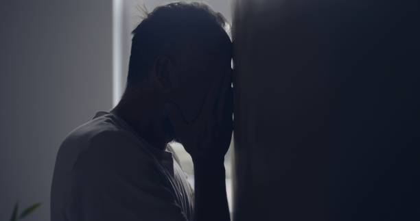 istock Close-up depressed man in the hall. Resting forehead against wall 1498902224
