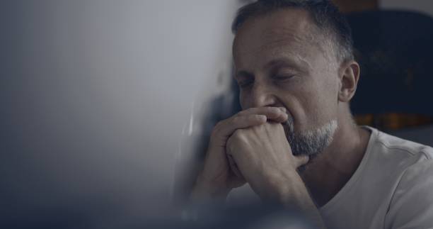 istock Close-up depressed man sitting alone in front of computer screen hiding face in hands. Job burnout 1498902252