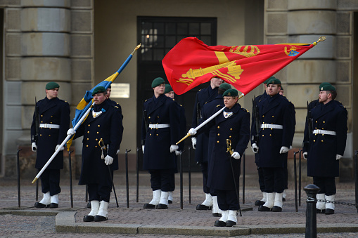Royal Guards waving flags outside the Stockholm Palace at a guard rotation, on a sunny day in Stockholm, Sweden