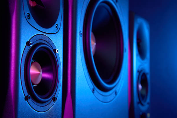 Multimedia acoustic sound speakers with neon lighting. Sound audio system with two satellites and subwoofer on dark background.