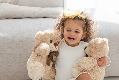 Cute little girl playing with teddy bears in the living room