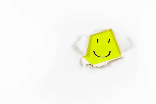 istock yellow smiley face showing off through ripped paper 1498907491