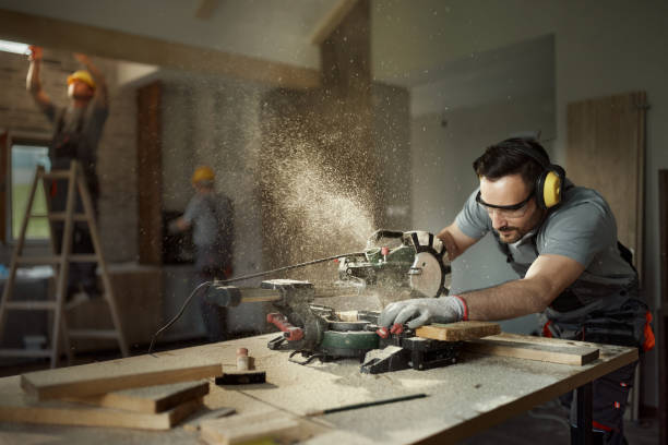 male carpenter cutting wood plank with electric saw at construction site. - elektrische zaag stockfoto's en -beelden