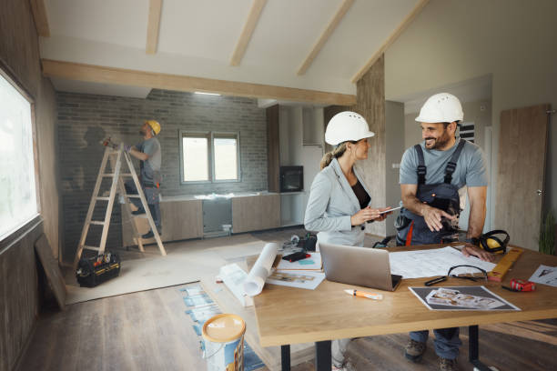 istock Happy female inspector and manual worker talking during renovation process. 1498907915