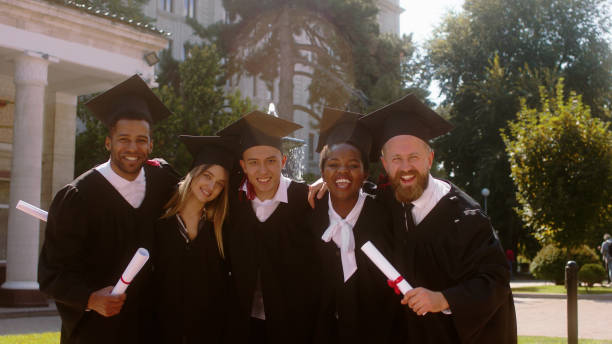 istock Great looking young students graduates hugging in group all together discussing and feeling excited in front of the camera in the college garden 1498908279