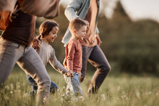 des enfants insouciants qui courent avec leurs parents dans le parc. - family outdoors child bonding photos et images de collection