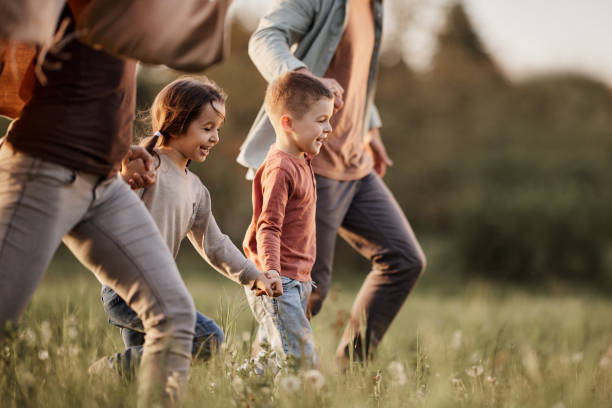 Carefree kids running with their parents in the park. stock photo