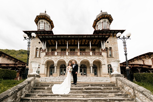 The bride and groom posing together on the stairs of a castle