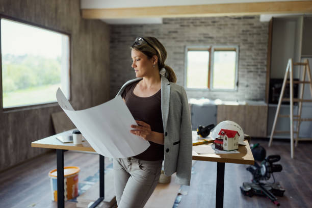 istock Young female building contractor analyzing housing plans at construction site. 1498909194