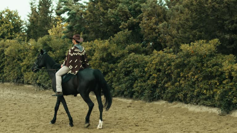 Man horseback to a horse in a ranch with cowboy dresses