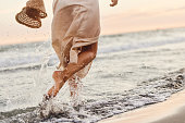 Back view of playful woman running through sea on the beach.