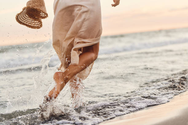 Vista de trás da mulher brincalhão correndo pelo mar na praia. - foto de acervo