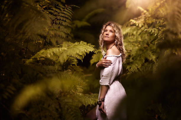 Young carefree woman day dreaming among greenery in rainforest.