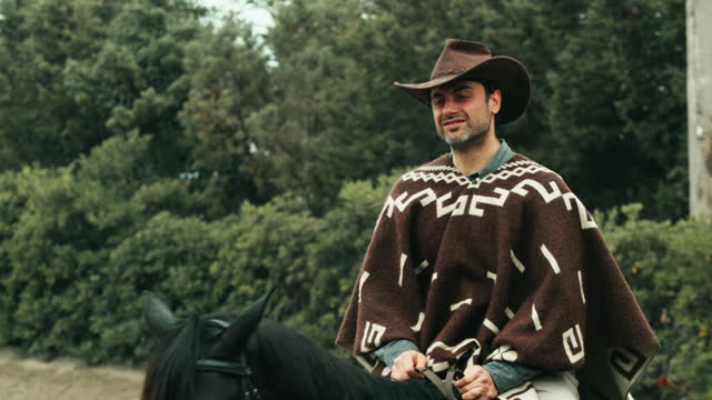 Man horseback to a horse in a ranch with cowboy dresses