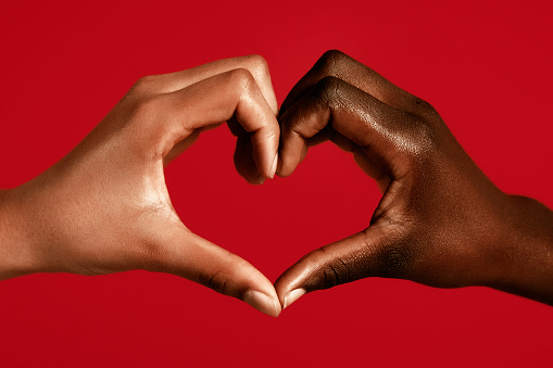 Diverse hands making a heart symbol against red background