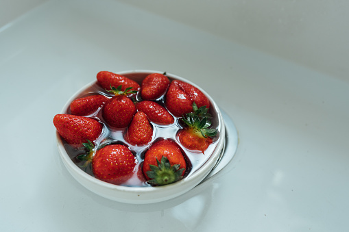 Bowl full with strawberry and water in the kitchen sink
