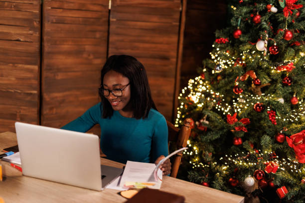 istock Female university student using laptop and reading a book when studying for exam during Christmas holidays 1498918192