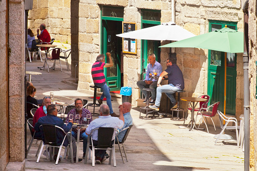 Street view, old stone houses  and sidewalk cafes in Ribadavia, ribeiro area, Ourense province, Galicia, Spain. Incidental people sitting in jewish quarter.