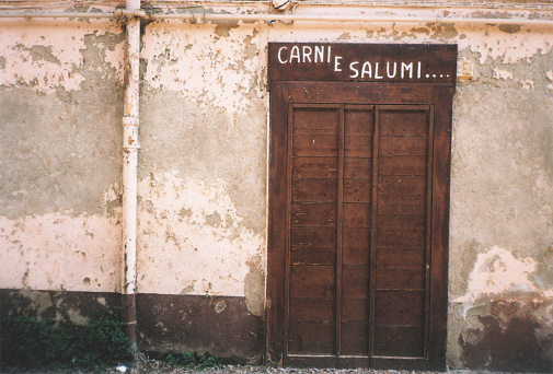 Old Wooden Door of a Butcher Shop with Hand Written Sign. Abandoned Building in San Giuliano Milanese, Milano Province, Italy. FIlm Photography