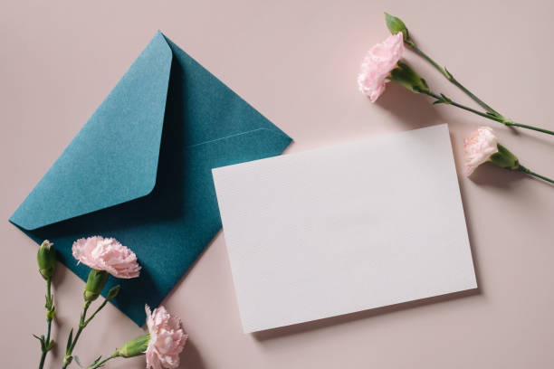 istock White blank greeting or invitation card and envelope with flowers decoration on pink background. Mock up presentation. 1498924018