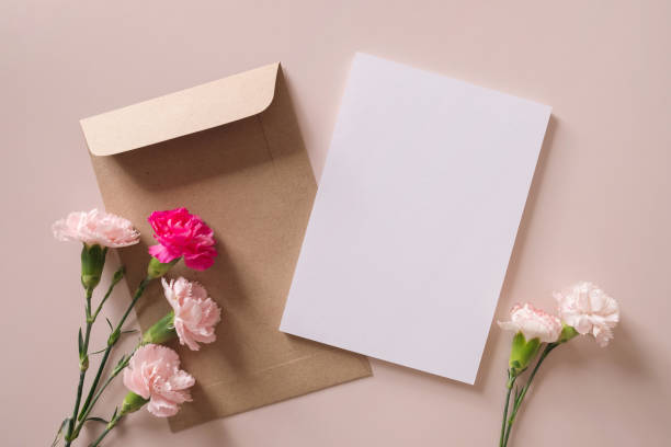 istock White blank greeting or invitation card and envelope with flowers decoration on pink background. Mock up presentation. 1498924019