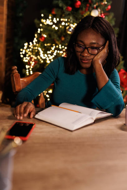 istock Young woman pondering while writing in a diary and waiting to receive a text message via smart phone 1498924141