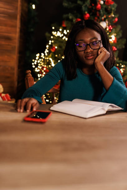 istock Young woman pondering while writing in a diary and waiting to receive a text message via smart phone 1498924879