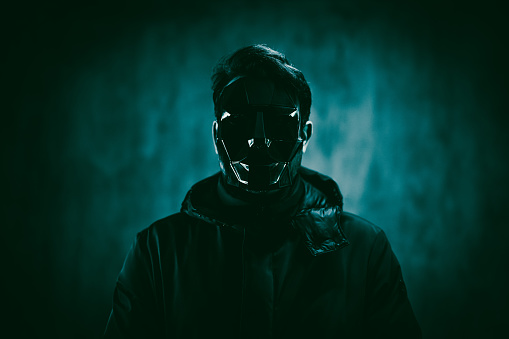Scary man wearing a mask and standing under neon lights.