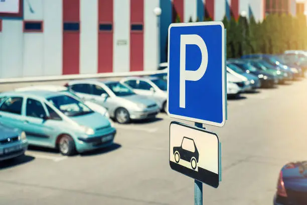 Parking blue sign mounted on pole at urban carpark on summer day outdoor. Pay or free car parking concept.