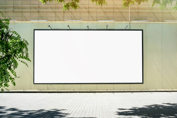 Big empty white billboard mounted on city mall wall outside. Big empty white billboard mounted on city mall wall outside. Commercial advertising and promotion product. Merchandise and marketing concept. store wall surrounding wall facade stock pictures, royalty-free photos & images