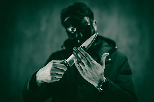 Scary man in a black mask holding a knife.
