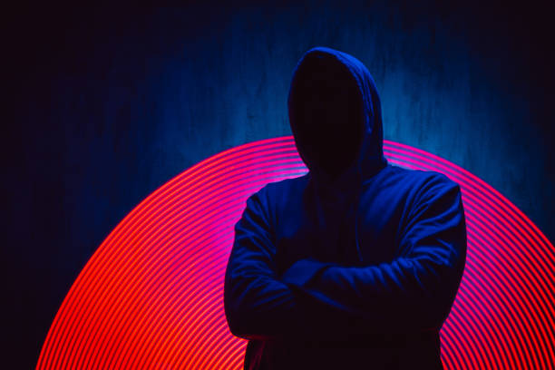 gruseliger gesichtsloser mann in einem kapuzenpullover unter neonlichtern - computerhacker stock-fotos und bilder