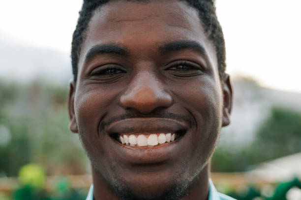 istock Young African man smiling on camera with park city on background 1498926209