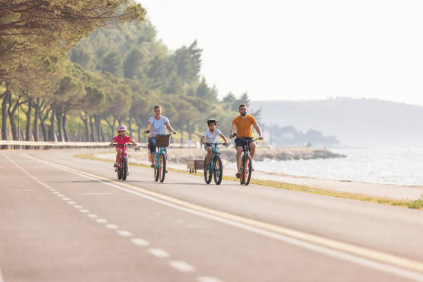 istock Two kids with parents riding bikes along a sea coastline, front view 1498928014