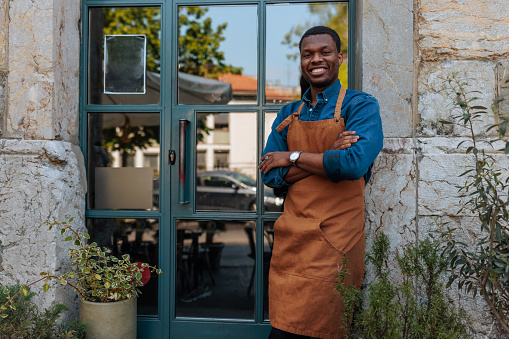 Portrait of young African-American business owner standing at the bar entrance.