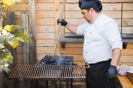Chef using coal barbecue and mixing the coal with a shovel