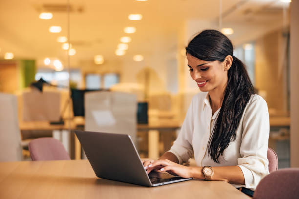 istock Smiling female boss using a laptop, working on a new project, sitting at the office. 1498934217