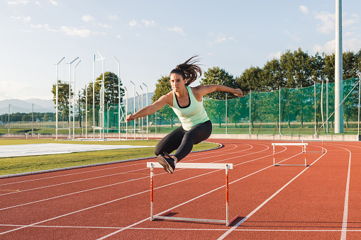 Woman in action of high jump a stadium at night. Sports banner. Horizontal copy space background