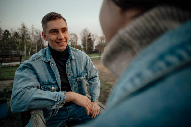 close up of a smiling beautiful young couple on the bench in park - human face heterosexual couple women men imagens e fotografias de stock