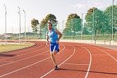 Young focused man running along an athletic track