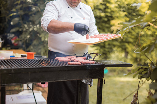 Chef preparing meat on a barbecue grill, ordering meet by shape