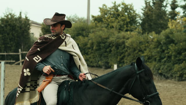Man horseback to a horse in a ranch with cowboy dresses