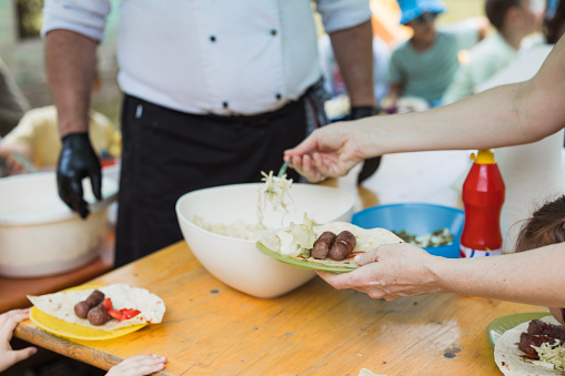 Female hand adding a salad to her meat plate