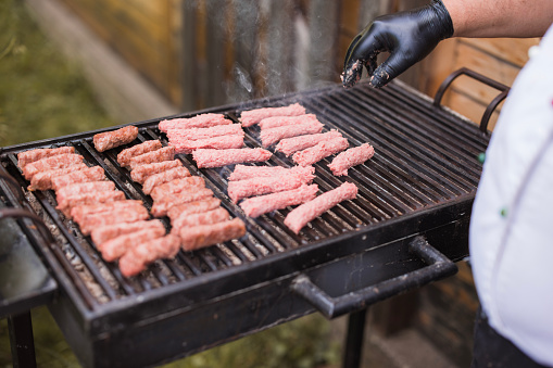 Chef preparing meat on a barbecue grill, ordering meet by shape