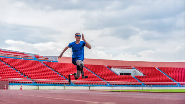 Asian male athlete with prosthetics runs at full speed, demonstrating a powerful practice on stadium track stock photo