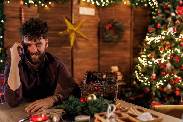 istock Young man talking on the phone while decorating a Christmas wreath 1498942435