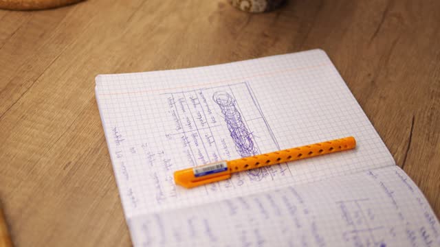 Close up shot of open copybook with squared sheets near mobile phone. High school or college student prepares for certification examination using smartphone.