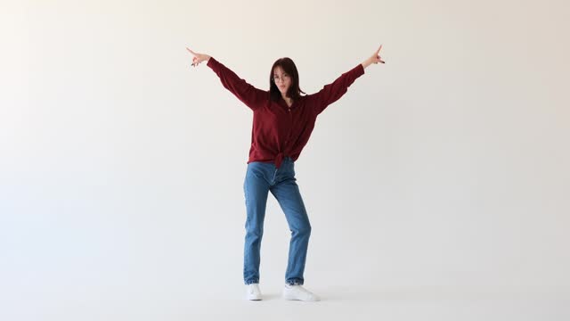 Attractive caucasian teenager girl joyfully dancing on a white background