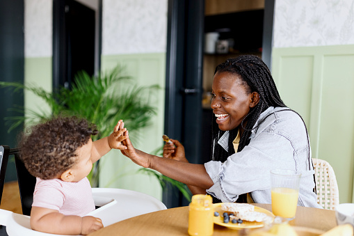 Playful child eating healthy food with his mother